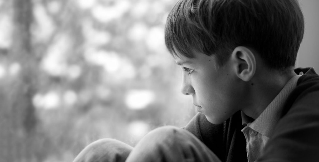 Sad teenager sitting on window